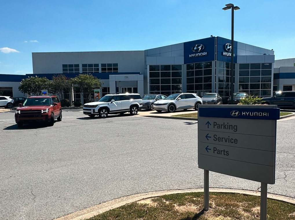 Front view of Crain Hyundai of Little Rock dealership with Hyundai vehicles parked out front and service sign in foreground